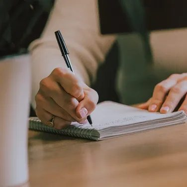 Notepad on a wooden desk being written in