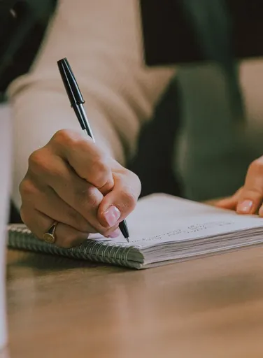 Notepad on a wooden desk being written in