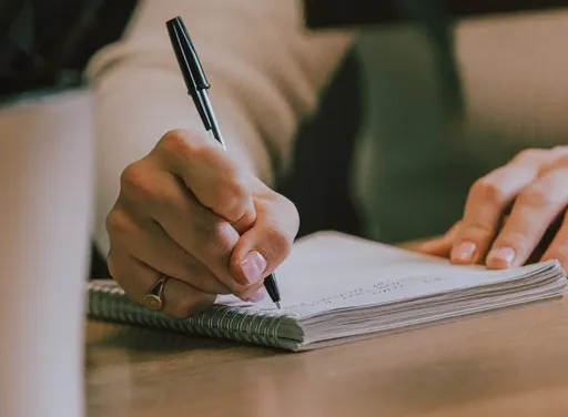 Notepad on a wooden desk being written in