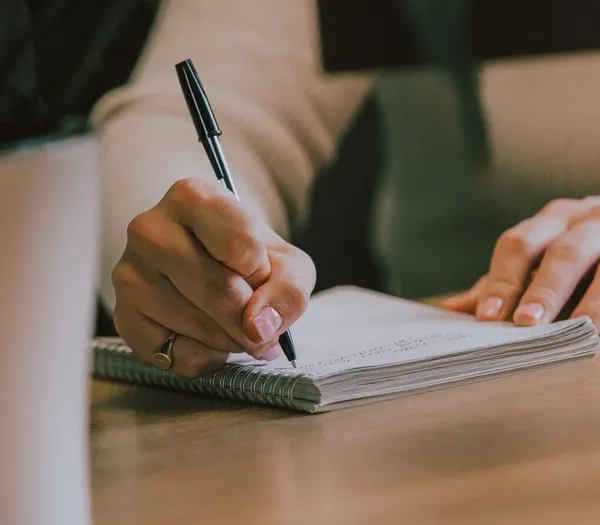 Notepad on a wooden desk being written in