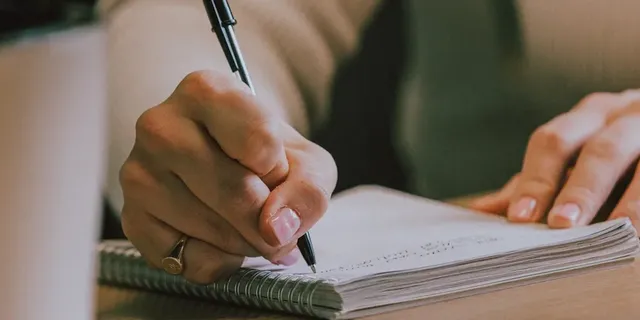 Notepad on a wooden desk being written in
