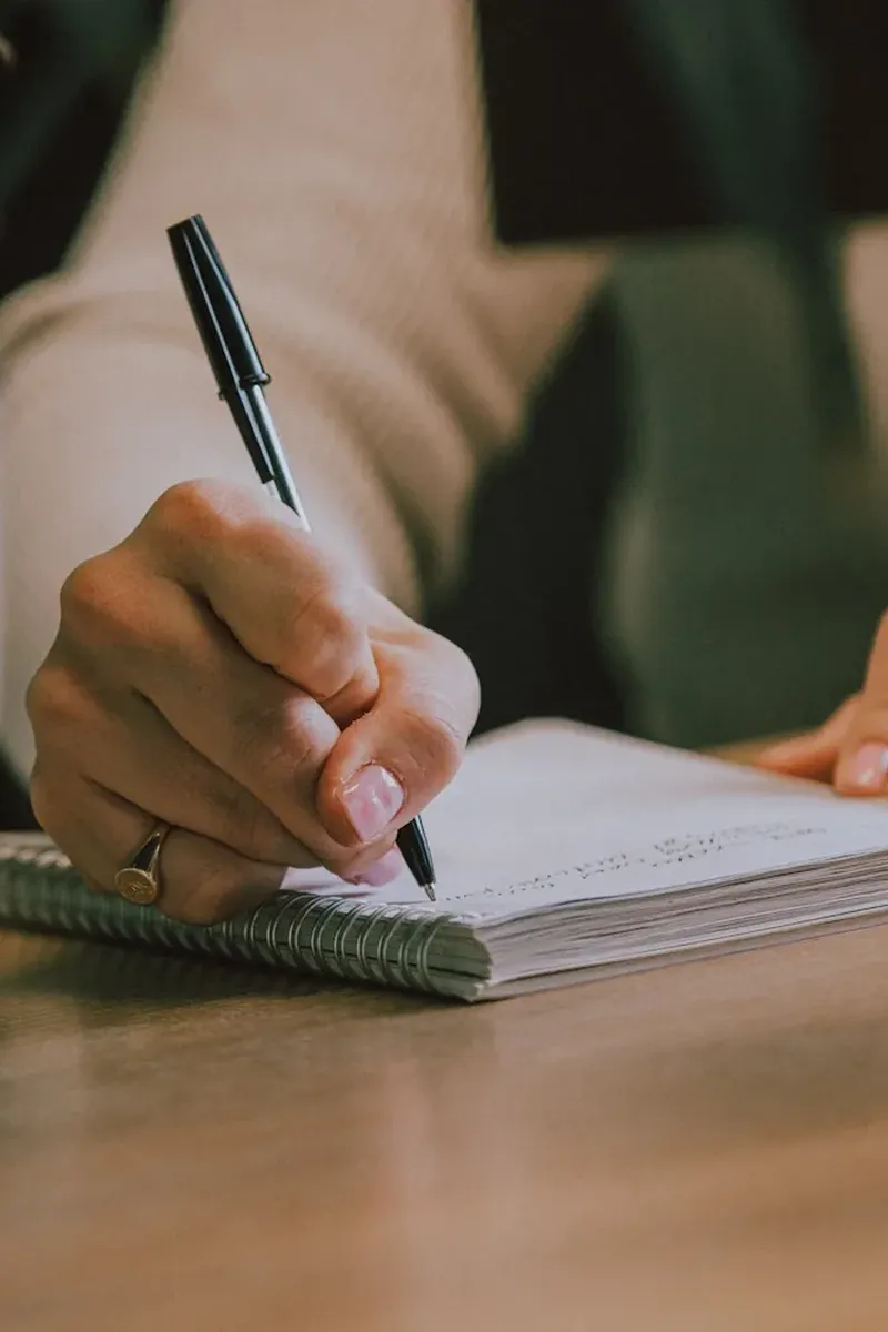 Notepad on a wooden desk being written in