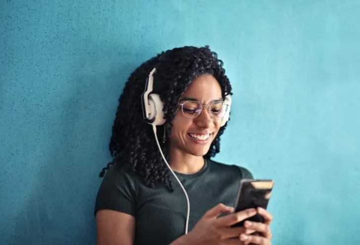 Digital Marketer looking at phone wearing headphones.